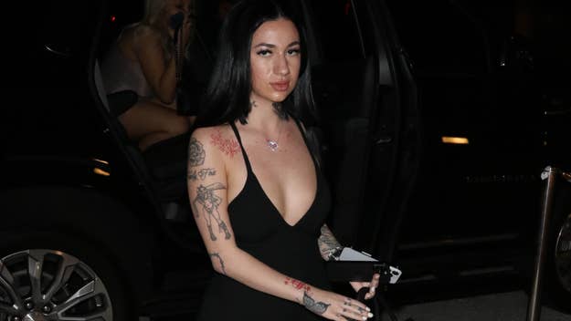 Bhad Bhabie exits a car wearing a form-fitting black dress with a deep V-neck, showcasing her tattoos