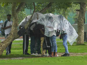 New Delhi: People shield themselves during rains, in New Delhi. (PTI Photo/Kamal...