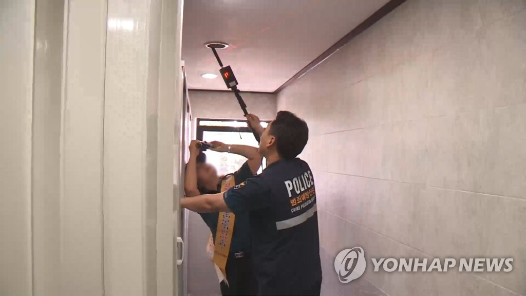 This undated photo, taken from footage provided by Yonhap News Television, shows officials conducting an inspection for illegal cameras in a women's restroom. (PHOTO NOT FOR SALE) (Yonhap)