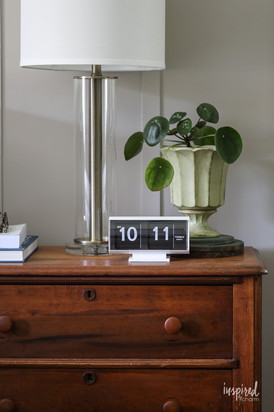 nightstand with clock, lamp, and plant with walls painted sherwin williams anew gray. 