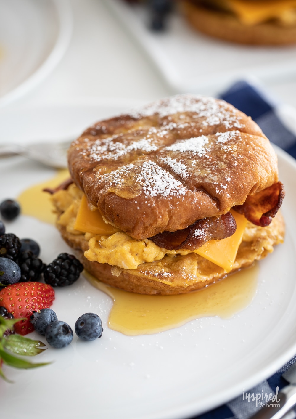 up close french toast breakfast sandwich on a plate with berries.