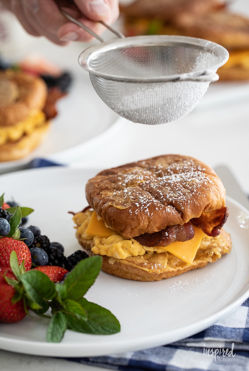 adding powdered sugar to french toast breakfast sandwiches.