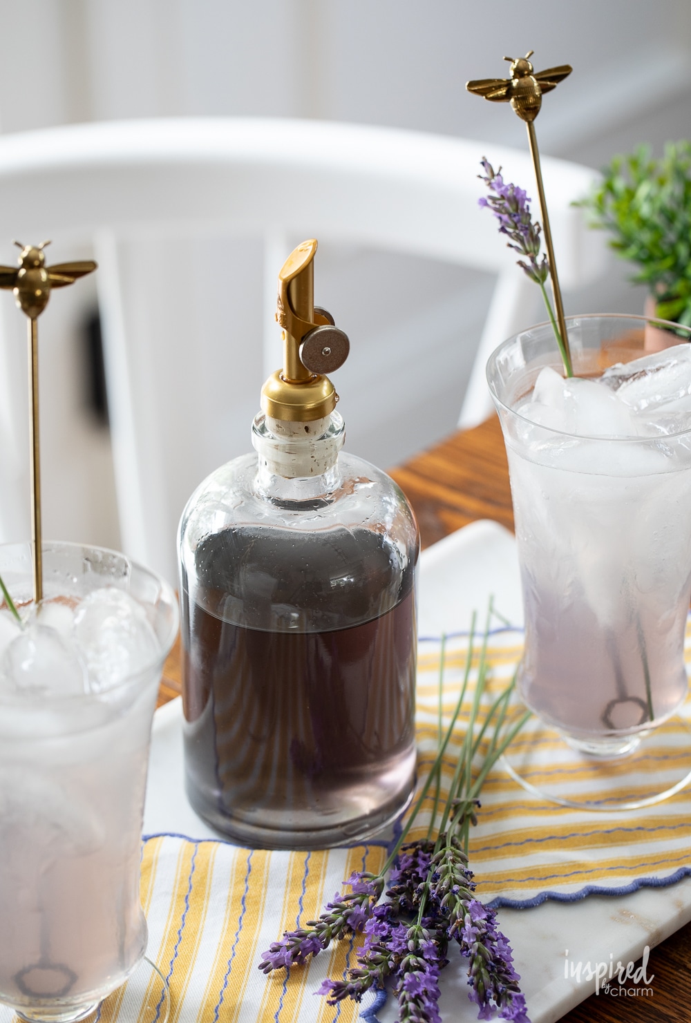 bottle of lavender simple syrup next to glasses of lavender lemonade.