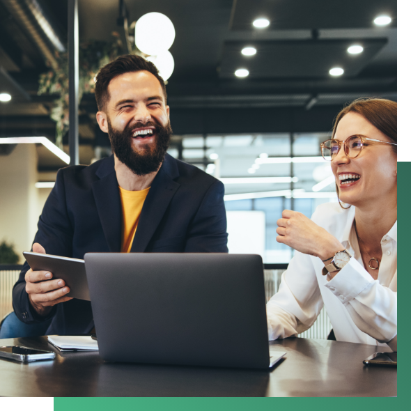 Intelygenz Vass - Hero image of two business people sitting around with laptops and ipads laughing to each other