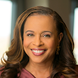 A poised Black woman with long wavy hair smiles at the camera