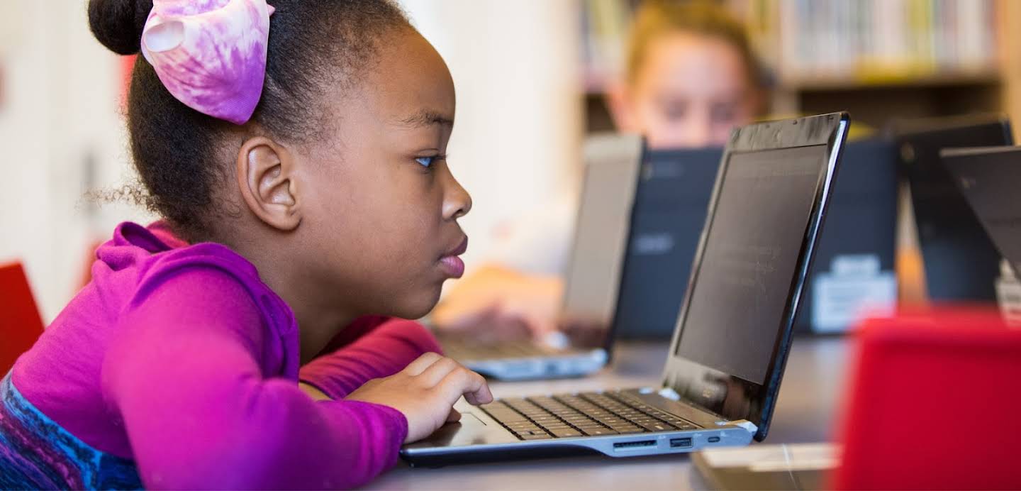 Una niña negra usa una Chromebook en un aula.