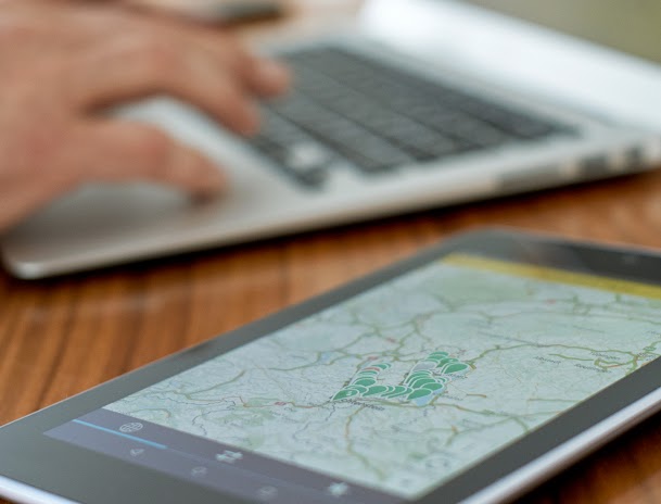 Personne en train de travailler sur un ordinateur portable, avec une carte affichée sur une tablette