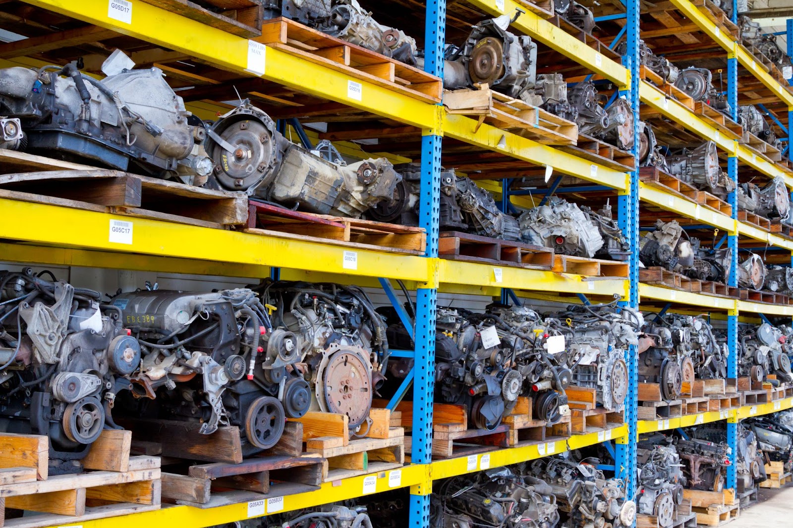 Rows of used engine blocks sit on wooden planks, and are stacked together on yellow shelves