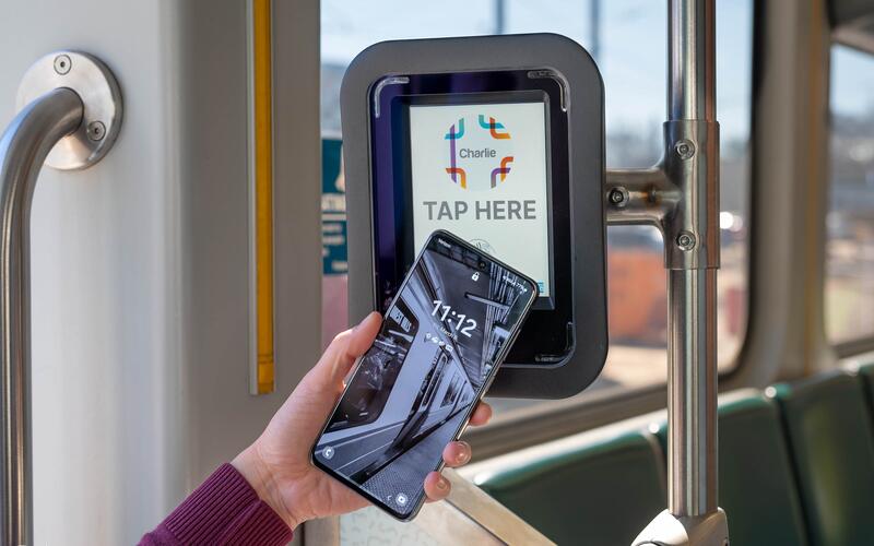 Rider tapping phone on Green Line Charlie reader that reads tap here