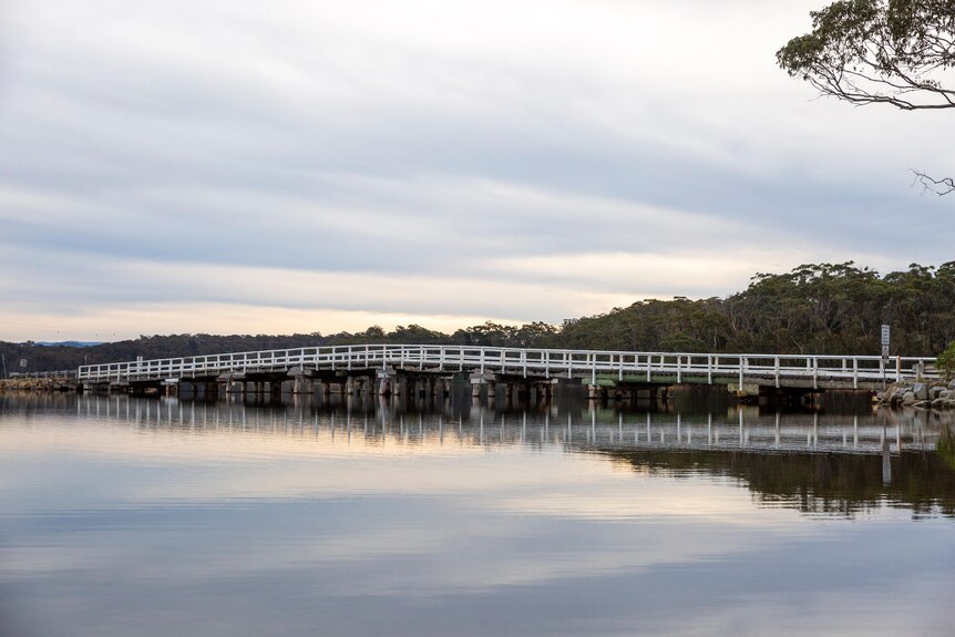 A white wooden arc-shaped bridge across Wallaga Lake.