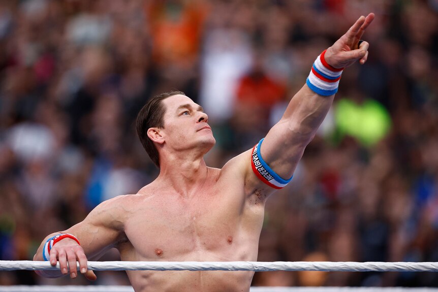 A shirtless man poses in a wrestling ring.