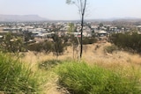 A grassy hill overlooking an outback city.