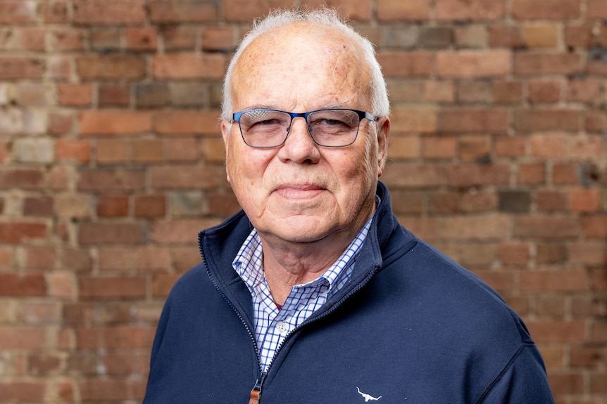 Headshot of an older man with grey hair and glasses.