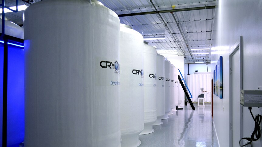 A row of large white tanks that each read "Cryonics Institute" in a line