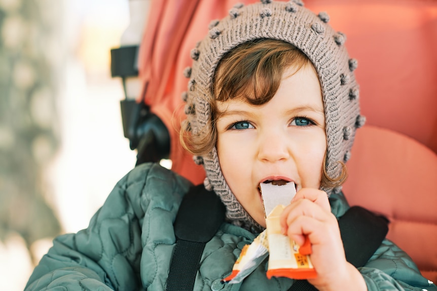 toddler in pram eating a fruit bar