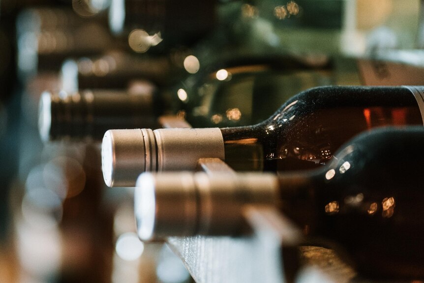 A close up of wine bottles on a shelf in a bottle shop.