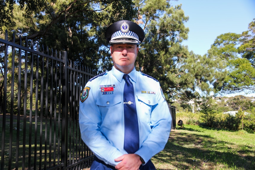 Man standing in a police uniform.