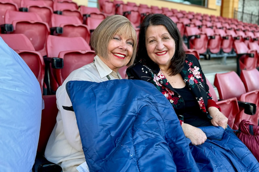 Two people sit alongside one another with sleeping bags.