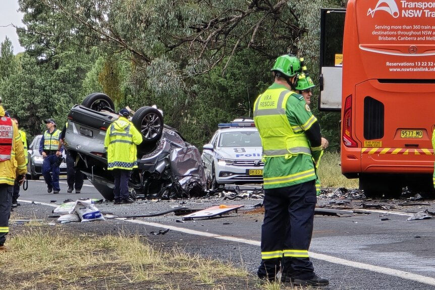  A car crash scene, showing a car flipped over, and a police car and a bus