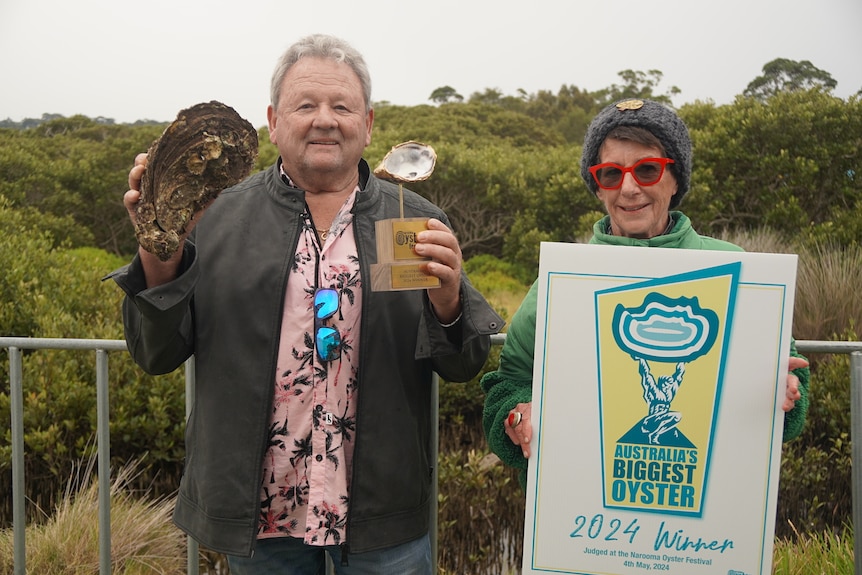 Man holds large oyster alongside his trophy