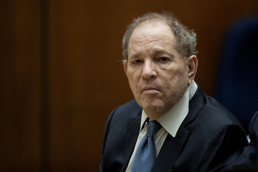 Harvey Weinstein dressed in a suit, sitting in a court room 