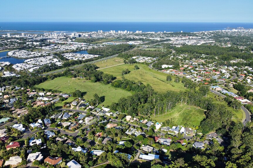 An aerial view showing farmland and all of the development around it with the ocean in the background.