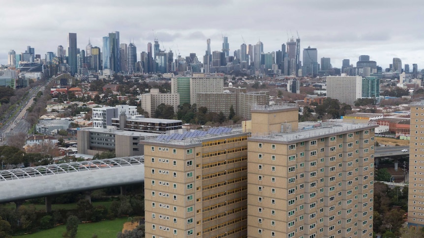 two public housing towers can be seen with the Melbourne city skyline in the background