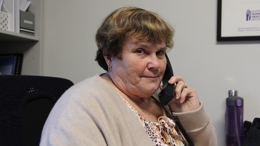 Woman holding black phone receiver looking at camera. 