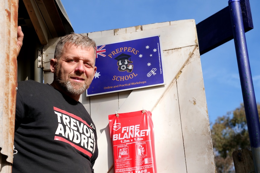 Trevor Andrei stands in a short with his name on the front at his property in regional Victoria on a summer day