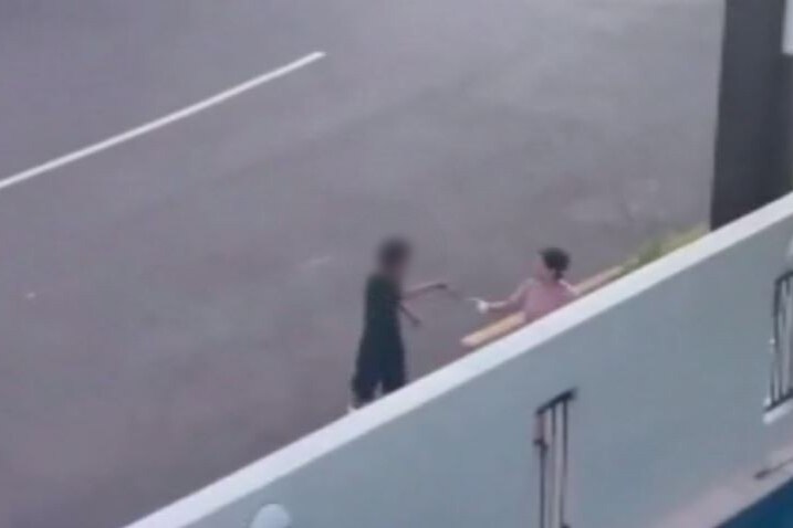 a blurred image of a boy holding a knife to a woman on the street