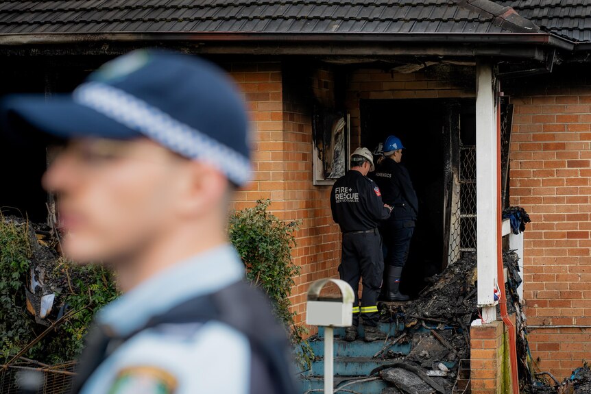 Police and fire inspectors outside a burnt-out home.