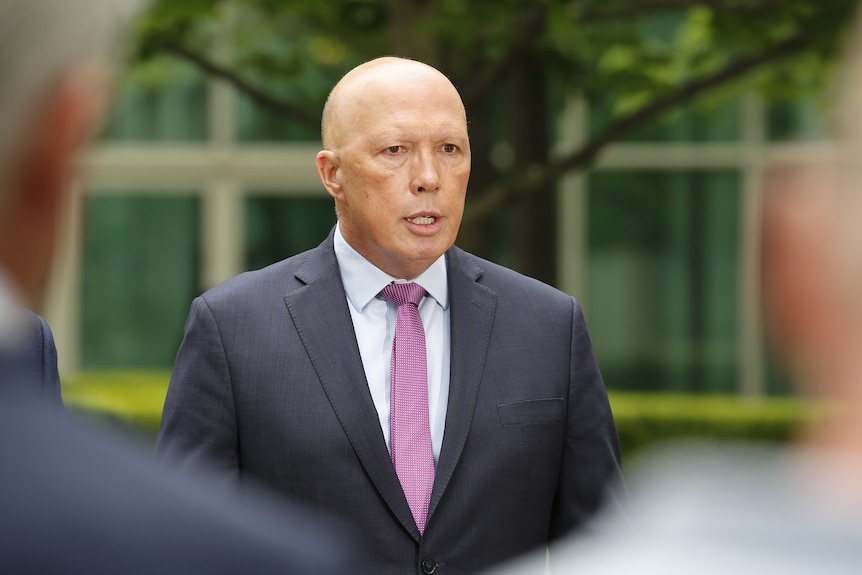 A man with a shaved head, wearing a suit.