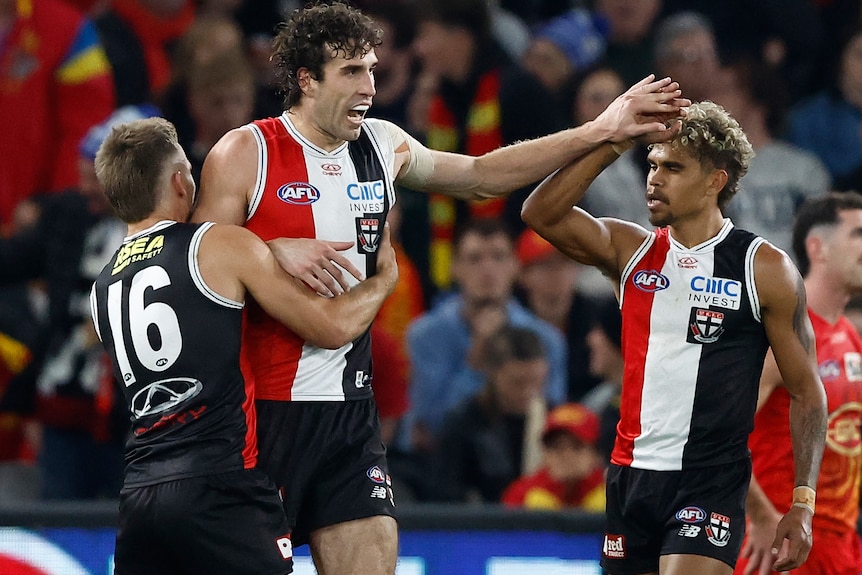 Three St Kilda AFL players celebrate against the Gold Coast Suns.