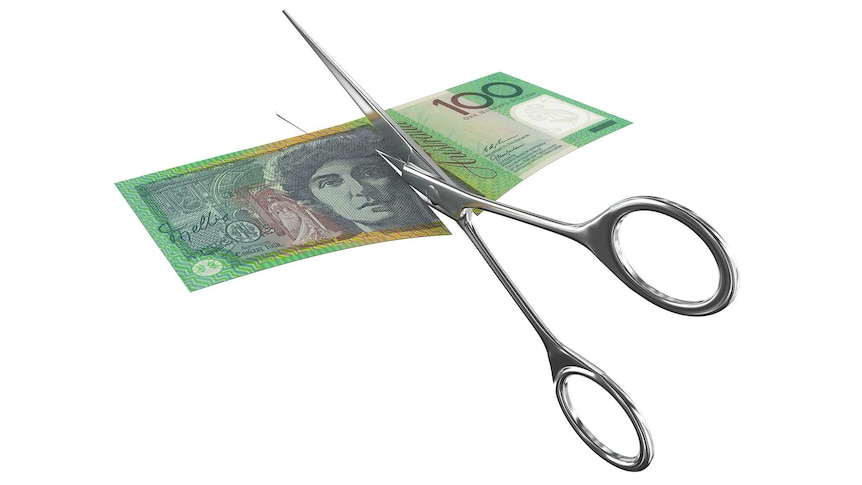 Scissors cutting through a $100 Australian bill 