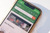 A phone screen displays Booktopia's green and white app with a search bar visible