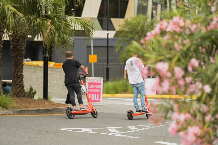 Unidentified people without helmets riding electric scooters in Brisbane.