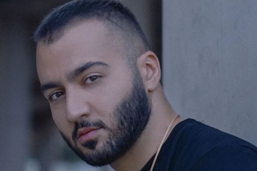 Headshot of Iranian man looking at the camera with his body facing the left with moody/blue hues