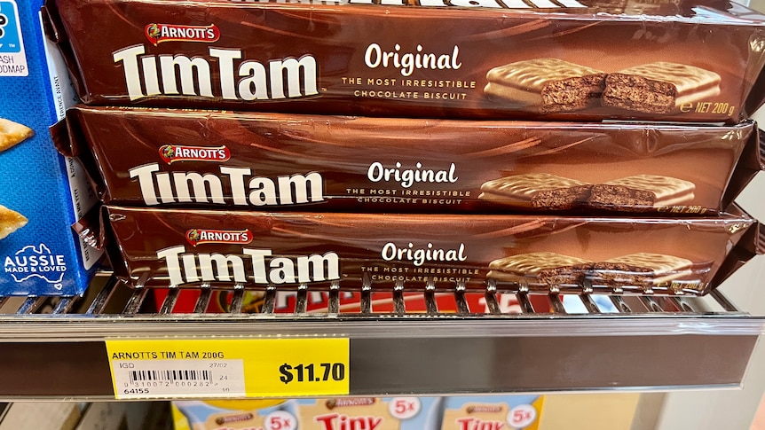 Packets of Tim Tam biscuits on a shelf, with a price tag saying $11.70