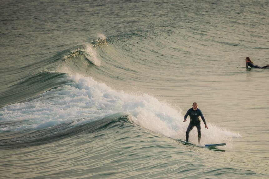 a man surfs on a wave