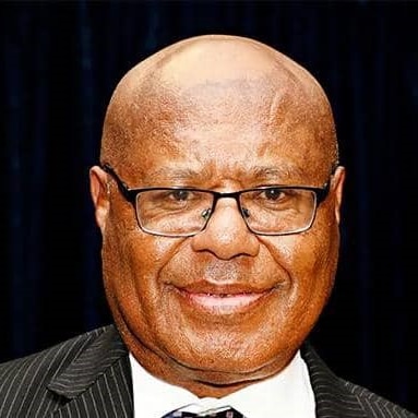 Headshot of a bald black man wearing glasses, suit and tie