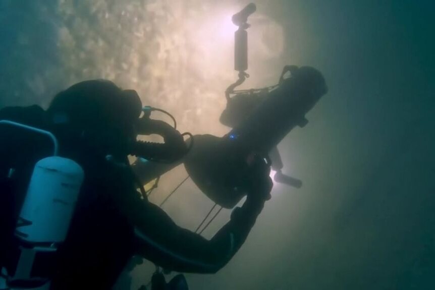 An underwater diver looking at a shipwreck.