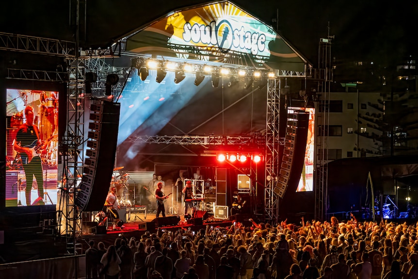 a crowd of people watch an artist perform o0n stage at night