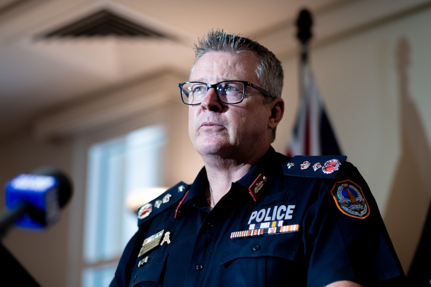 Jamie Chalker wears a police uniform and speaks at a press conferance.