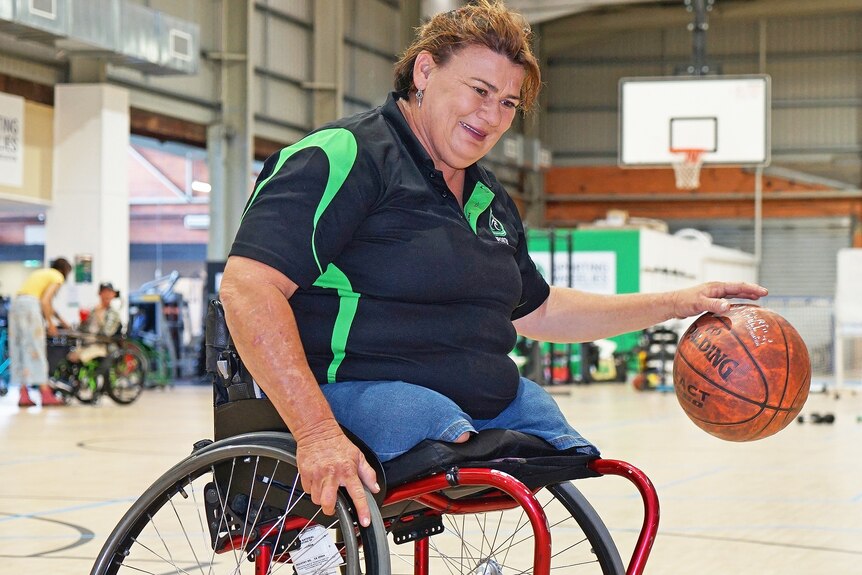 Wendy playing wheelchair basketball on an indoor court.