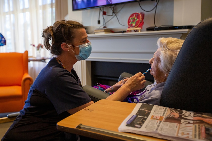 A nurse gives a covid test to an elderly lady