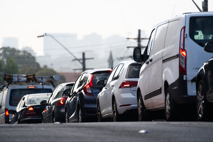 Image shows congestion and traffic delays. You can see cars, grey road on a gloomy day.