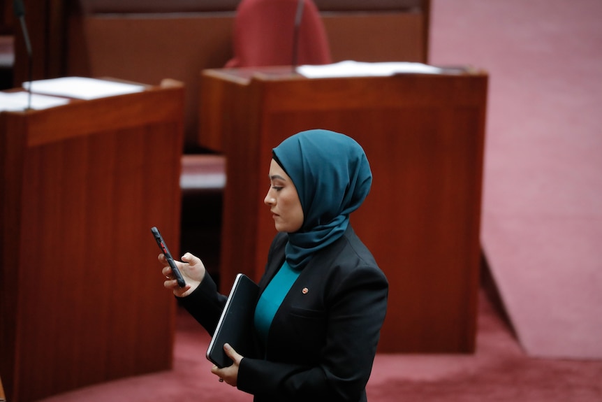 Payman stands on the floor of the senate, checking her phone.