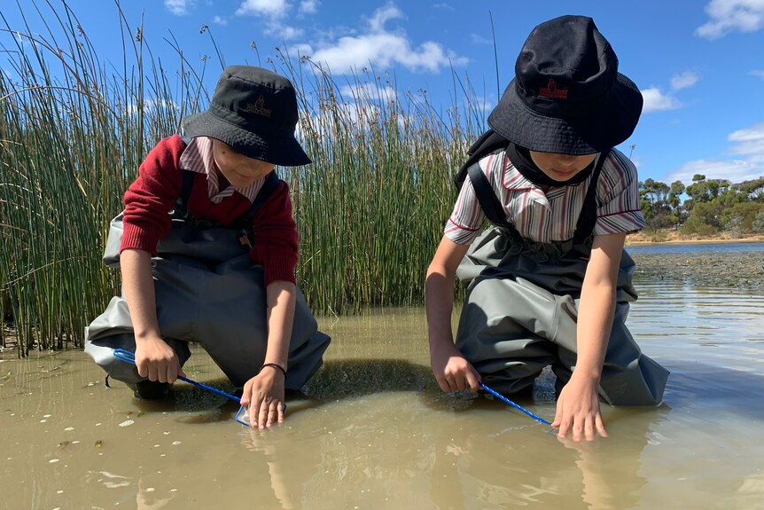 Photo of two children in river water.