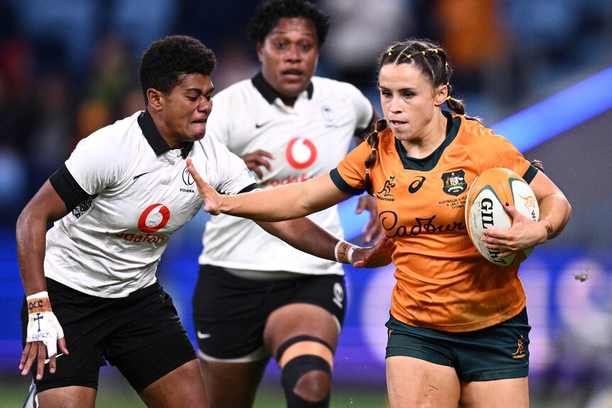 Desiree Miller holds the ball for the Wallaroos as she palms off a Fijiana opponent.