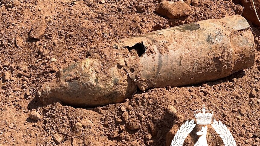 An old bomb is seen lying atop dirt at a construction site.